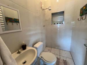 a white bathroom with a toilet and a sink at Chácara Bela Vista in Paraibuna