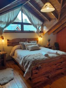 1 dormitorio con cama grande de madera y ventana grande en Tierras del Sur II en Villa La Angostura