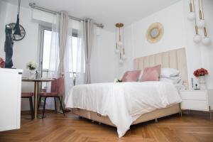 ein weißes Schlafzimmer mit einem Bett und einem Tisch in der Unterkunft Paris' Premium Romantic Studio in Paris