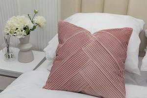 ein rotes und weißes Kissen auf einem Bett mit einer Blumenvase in der Unterkunft Paris' Premium Romantic Studio in Paris + 30 Fotos