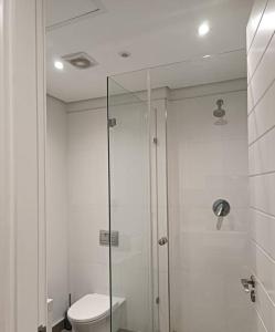ウムランガにあるModern comfy studio apartment with poolsのバスルーム(トイレ、ガラス張りのシャワー付)
