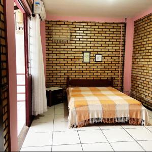 um quarto com uma cama numa parede de tijolos em La Serena em Florianópolis