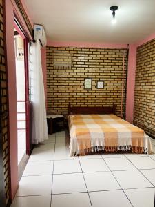 um quarto com uma cama e uma parede de tijolos em La Serena em Florianópolis
