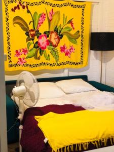 a yellow blanket is hanging above a bed with a fan at Mango in Le Carbet