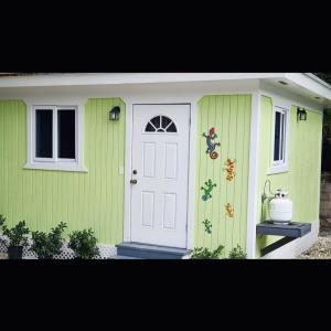 a green house with a white door and a window at Budget & Basic in Local Neighborhood, 7min Drive to Downtown Nassau Beach Paradise in Nassau