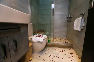baño con aseo y ducha con flores rojas en el suelo en Pyramids Land Hotel en El Cairo