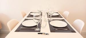 a table with white plates and wine glasses on it at Lindo Apartamento Moderno e Reformado na Barra in Rio de Janeiro