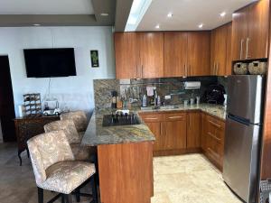 a kitchen with wooden cabinets and a stainless steel refrigerator at Come, Enjoy & Relax at Rio Mar Cluster II, Rio Grande, PR in Rio Grande