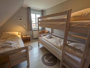 a bedroom with two bunk beds and a window at Ferienhaus Ellen, OG Whg in Utersum
