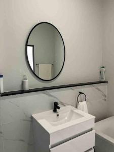 a white bathroom with a sink and a mirror at 3 Elizabeth Place Luxury Penthouse - Beautiful self catering 2 bedroom unit next to the Lagoon with free WiFi - swimming pool gym and restaurant - Perfect for a small family in Midrand
