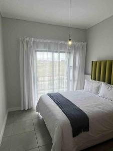 a bedroom with a large bed and a window at 3 Elizabeth Place Luxury Penthouse - Beautiful self catering 2 bedroom unit next to the Lagoon with free WiFi - swimming pool gym and restaurant - Perfect for a small family in Midrand