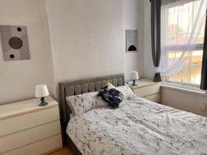 a bedroom with a bed with two lamps and a window at A little slice of London in London