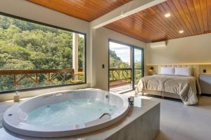 een slaapkamer met een bad en een bed in een kamer bij Pousada Alpenhof in São Pedro de Alcântara