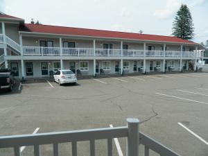 a white car parked in front of a white building at Hilltop Motel & Restaurant in Grand Falls