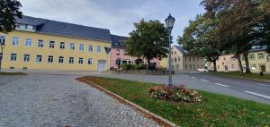 a large yellow building with a street light and flowers at Die Alte Bäckerei in Jöhstadt