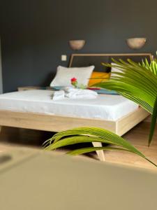 a bed with white sheets and a green plant at LESSENCIEL in Dzaoudzi