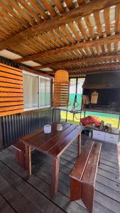 einem Holztisch und einer Bank auf einer Terrasse mit einem Grill in der Unterkunft Casa en alquiler El Detalle Punta Negra in Punta Colorada
