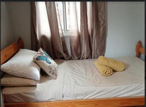 a bed with white sheets and pillows and a window at The City Dweller Kingaroy in Kingaroy