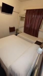 2 camas en una habitación pequeña con ventana en Hotel Cristal en Mendoza