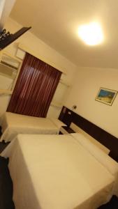 2 łóżka w małym pokoju z oknem w obiekcie Hotel Cristal w mieście Mendoza