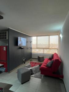 a living room with a red couch and a flat screen tv at Apartamento en Metro Ñuble in Santiago