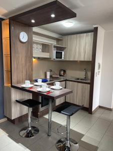 a kitchen with a table and chairs and a clock at Apartamento en Metro Ñuble in Santiago