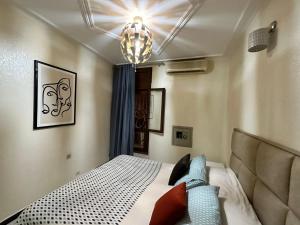 sypialnia z łóżkiem i żyrandolem w obiekcie Jawhara Jacobs apartment w Fezie