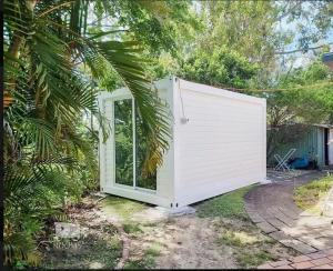 a small white shed with a window in a yard at The City Dweller Kingaroy in Kingaroy