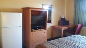 ein Schlafzimmer mit einem TV und einer Kommode mit einem Bett in der Unterkunft Budget Inn Sterling in Sterling