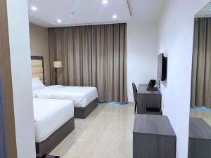 um quarto de hotel com duas camas e uma televisão em Wave View Hotel em Seeb