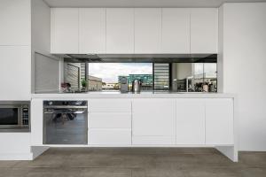 a kitchen with white cabinets and a stove top oven at EIGHT TWO NINE TWO III: BONDI BEACH in Sydney