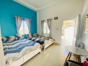 two beds in a room with blue walls and a table at Homestay BONO Mũi Né in Phan Thiet