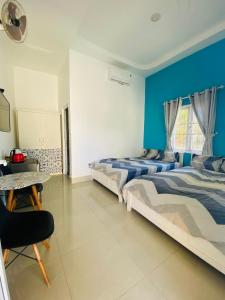 two beds in a room with a blue wall at Homestay BONO Mũi Né in Phan Thiet
