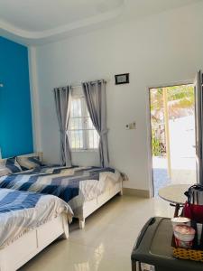 a bedroom with a bed and a table and a window at Homestay BONO Mũi Né in Phan Thiet