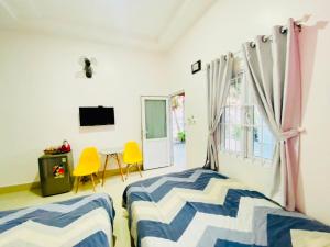 a bedroom with two beds and a table and a window at Homestay BONO Mũi Né in Phan Thiet