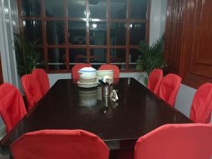 una mesa negra con sillas rojas y platos en ella en A.P.S. Lodge en Darjeeling
