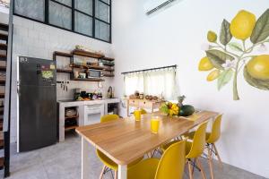 a kitchen with a wooden table and yellow chairs at Manao Seaview Pool Villa 25 - 5 Mins Walk To The Beach in Ko Lanta