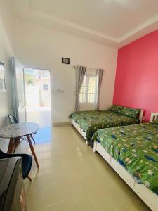 a bedroom with two beds and a table and a window at Homestay BONO Mũi Né in Phan Thiet