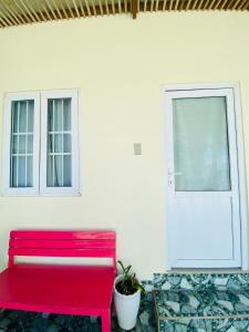 a red bench in a room with a door and a plant at Homestay BONO Mũi Né in Phan Thiet