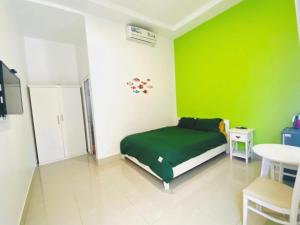 a green bedroom with a bed and a table at Homestay BONO Mũi Né in Phan Thiet