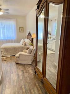 a bedroom with a mirror and a bed and a chair at The Shopkeeper's Cottage ~ CHIC! in Amador City