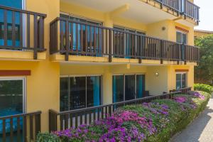 a yellow building with balconies and purple flowers at Palapa Beach Oasis in Jan Thiel