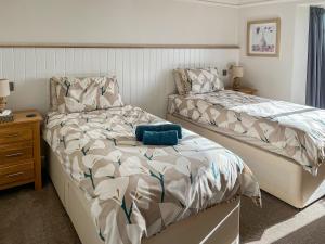 a bedroom with two beds next to a nightstand and a bed sidx sidx sidx at Beacon Cottage in Ivybridge