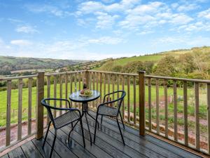 a table and chairs on a deck with a view at Westpitt Farm - The Hay Loft in Tiverton