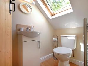 a bathroom with a toilet and a sink and a skylight at Charnwood Cottage in Dale