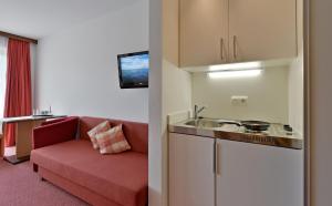 ein Wohnzimmer mit einem roten Sofa und einem Waschbecken in der Unterkunft Hotel Garni Tirol in Walchsee