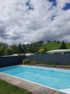 a blue swimming pool in front of a fence at Mayfair Court Motel in Tokoroa