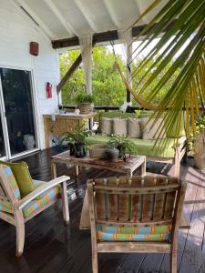 a porch with a green couch and two chairs at Hidden Paradise - Cottage in Nassau