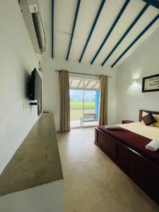 a bedroom with a bed and a tv and a window at RHO Sigiriya Lake Edge Retreat & Spa in Sigiriya