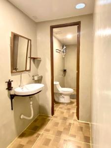 a bathroom with a toilet and a sink and a mirror at Laguno Bed And Breakfast Hostel in Moalboal